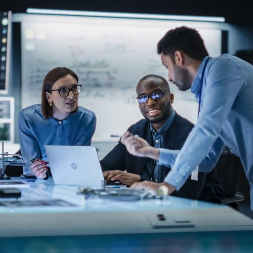 Two men and a woman strategizing around a computer.