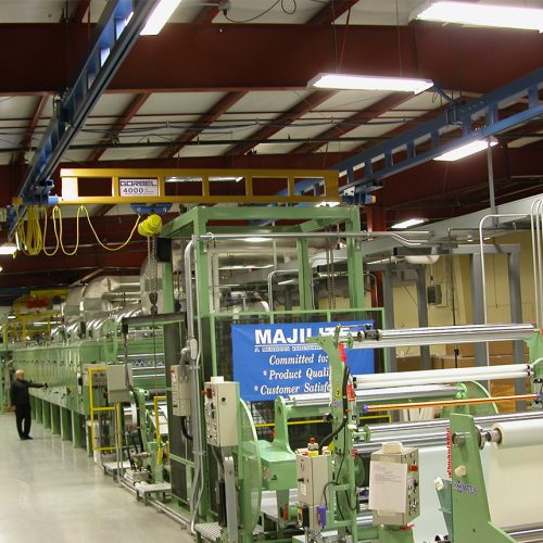 Machinery on the Majilite Custom production floor, showing a series of rollers, cutters, and laminations.